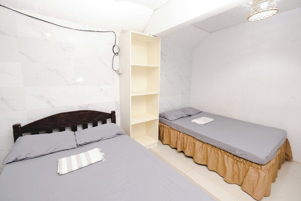 A bedroom with two beds, a wardrobe, and a hanging light fixture.