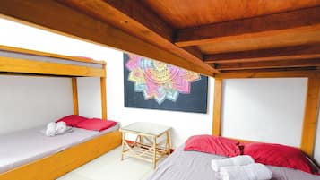 Ein Zimmer mit zwei Betten, einem kleinen Tisch und einem farbenfrohen Kunstwerk an der Wand.