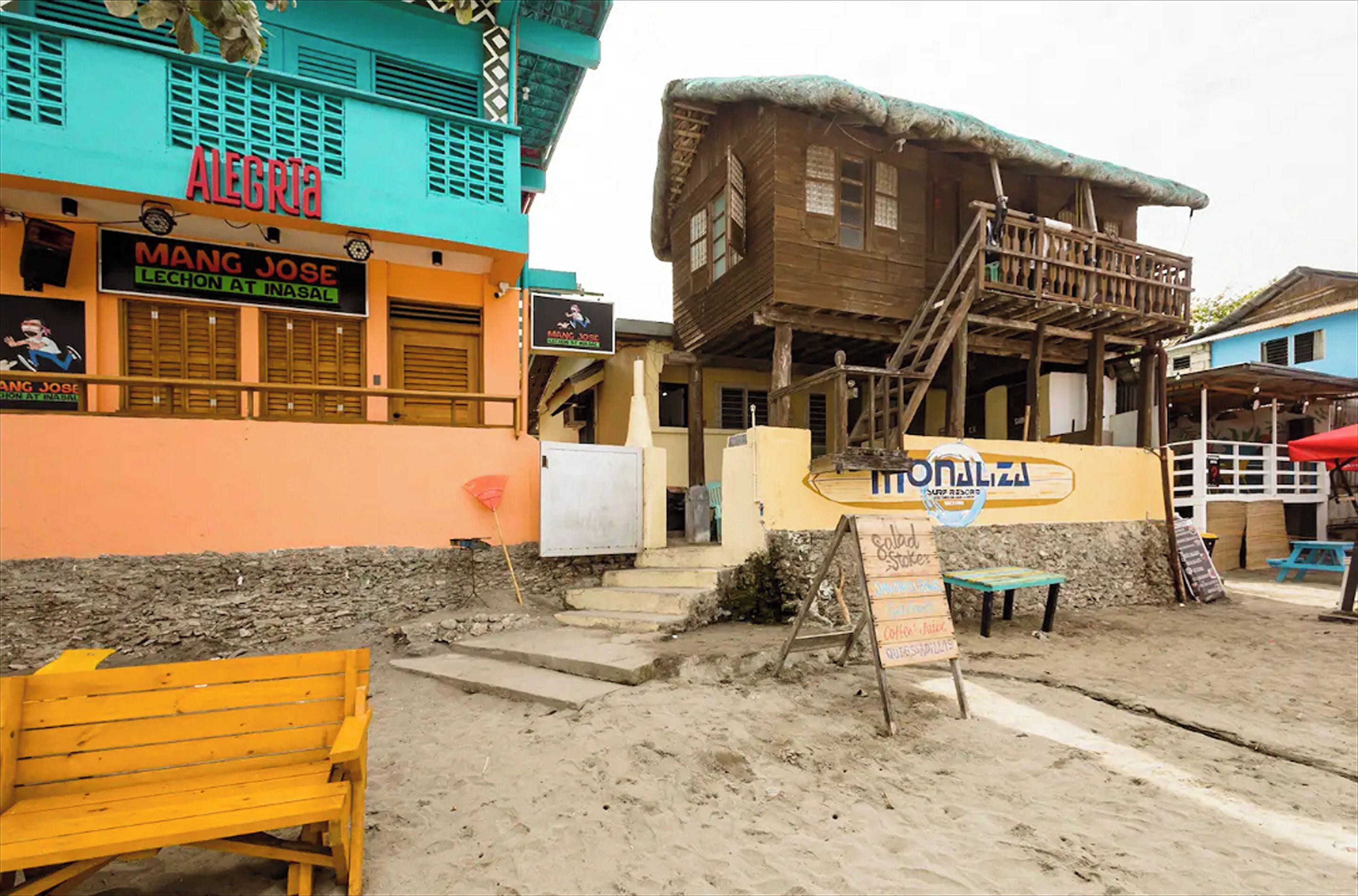 A beachside building with a sign for 'Mangal Jose Lechon at Inasal' and another for 'Monalisa Surf Beach'.