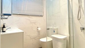 Un baño moderno con ducha de vidrio, inodoro y lavabo.