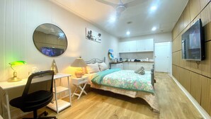 Un dormitorio moderno con cama, escritorio, silla y televisión montada en la pared.