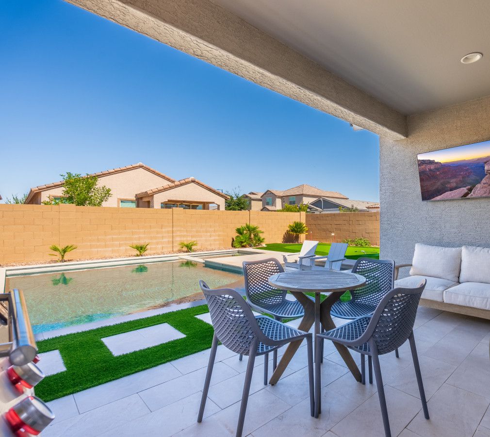 Une terrasse avec une piscine, du mobilier d’extérieur et une vue sur les maisons voisines.