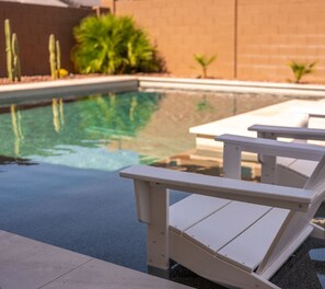A poolside area with white Adirondack chairs and a logo for 'Liqnq Property Group' on the ground. - Private Retreat House with Pool and Spa/Hot Tub Min from Westgate, Andretti Karting, and TWoods Golf (Phoenix)