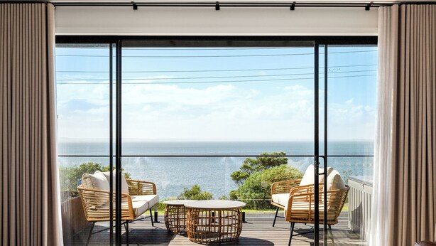 A balcony with wicker furniture and a view of the sea.