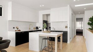 A modern kitchen with white cabinetry, a marble countertop, and a central island with a bar stool.
