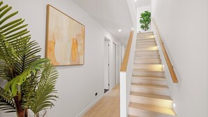 A staircase with wooden steps and a handrail, leading to a landing with a plant.