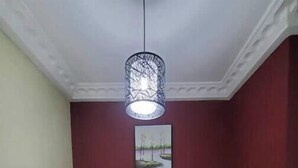 Uma área de refeições com uma mesa, cadeiras, um lustre pendurado e um quadro na parede.