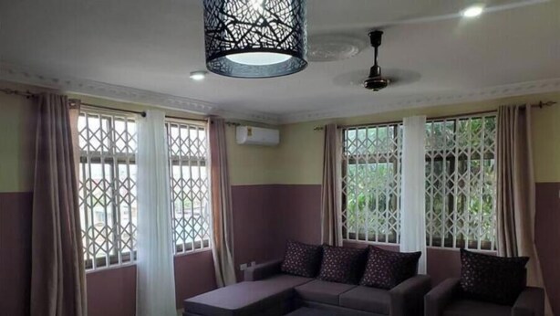 Uma sala de estar com sofá seccional, mesa de centro e luminária decorativa no teto.