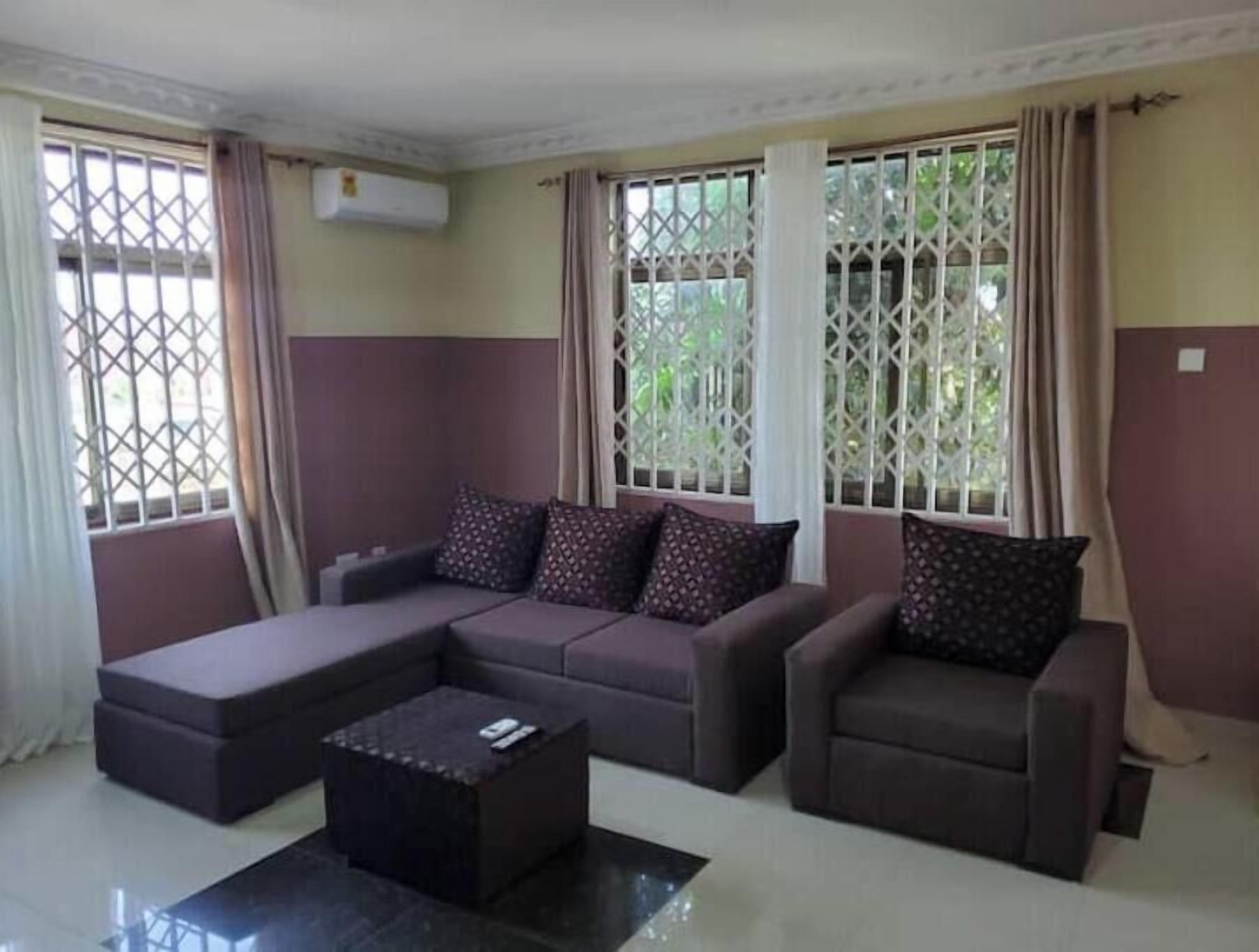 A living room with a sectional sofa, a coffee table, and a window with a view of greenery.