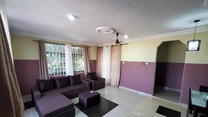 Uma sala de estar com um conjunto de sofá, uma mesa de centro e uma TV fixada na parede.