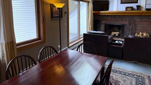 Un comedor con mesa y sillas de madera, chimenea y tragaluz.