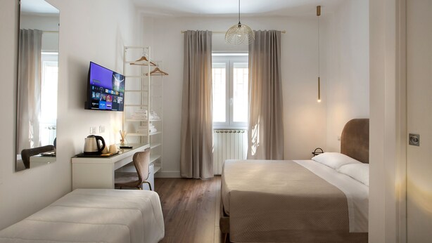 A hotel room with two beds, a desk with a TV, a chair, and a wardrobe. - CHARME HOLIDAYS PUCCINI (Rome)