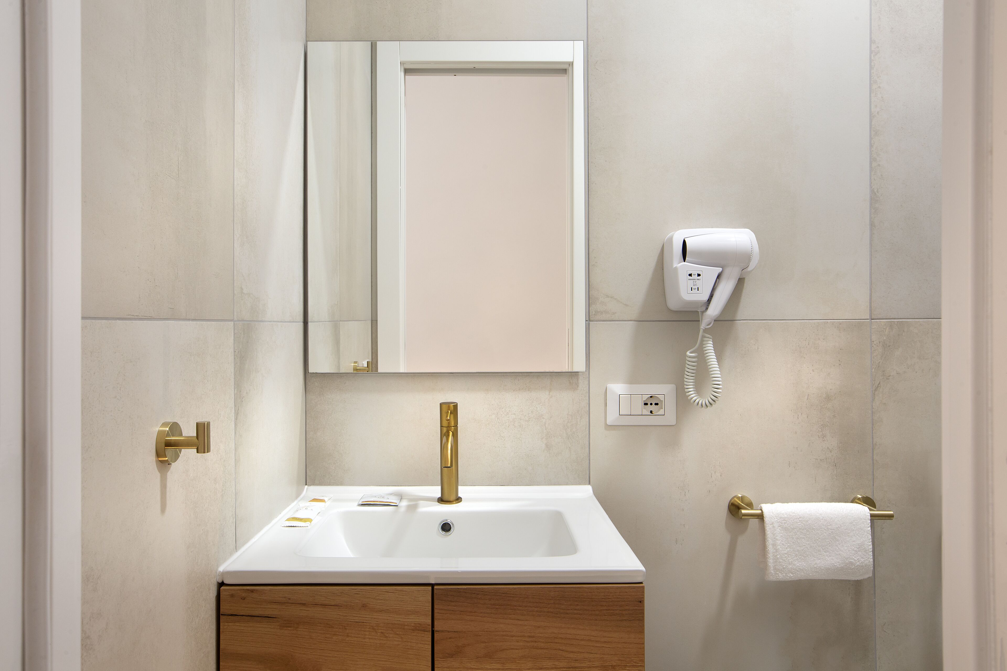 A bathroom with a white sink, gold faucet, and a towel rack.
