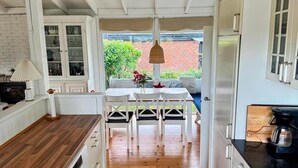 Une cuisine avec des meubles blancs, un plan de travail en bois et un coin repas comprenant une table et des chaises.