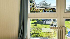 Une pièce dotée d’une grande fenêtre, d’un radiateur et donnant sur un jardin.