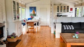 Une cuisine spacieuse avec un plancher en bois, un coin repas avec une table et des chaises, et un salon avec un canapé et une cheminée.