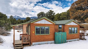 A wooden cabin with a porch, a green door, and a number '2' sign.