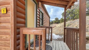A wooden cabin with a porch, a door, and a window.