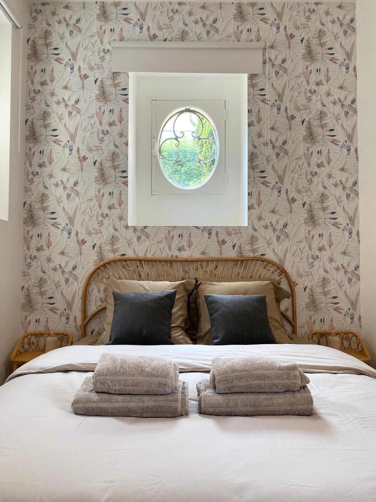 Una camera da letto con un letto, due cuscini, una finestra e un motivo floreale sulle pareti.