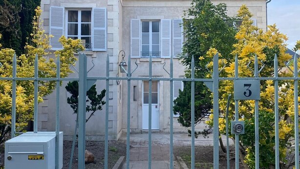 Une maison à deux étages, dotée d’une entrée fermée par un portail, d’une plaque portant le numéro 3 et d’un petit coffret de raccordement électrique.
