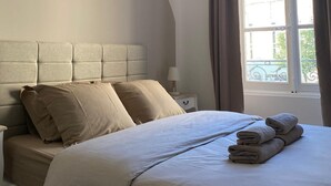 Une chambre à coucher avec un lit, une table de chevet, une lampe et une fenêtre avec des rideaux.