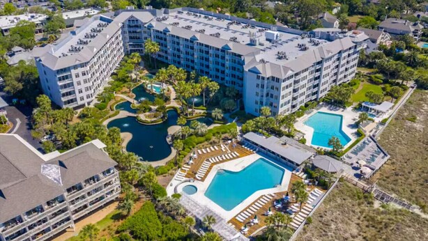 Un extenso complejo hotelero con varias edificaciones, una piscina central y zonas ajardinadas.