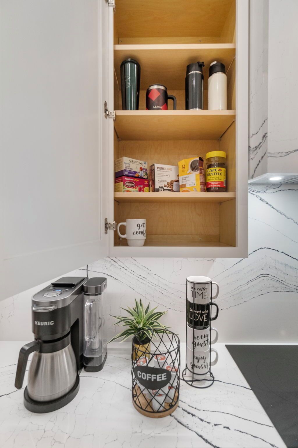 Cozinha com cafeteira, caneca e prateleira com produtos de café.