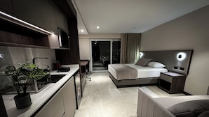 A modern hotel room with a bed, bedside table, and a desk with a chair. - AMERICA APARTMENTS (Santa Cruz)