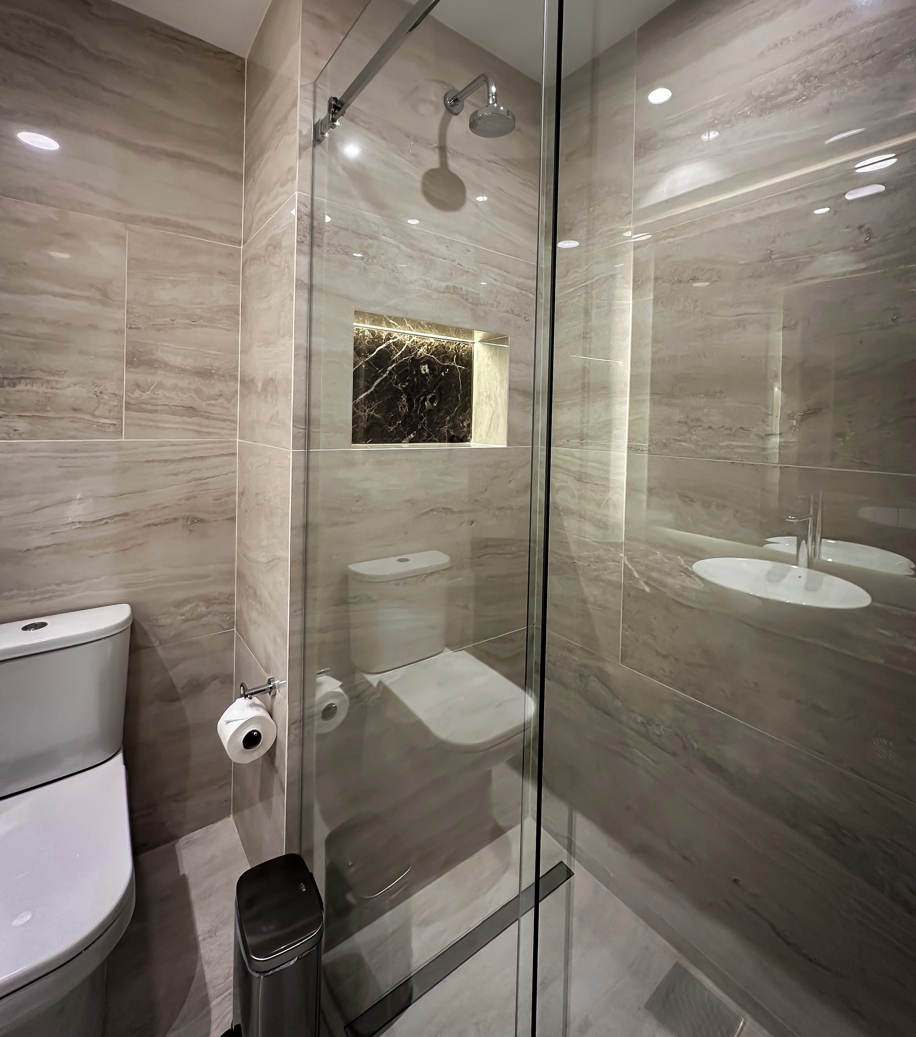 Une salle de bain moderne avec une douche à parois de verre, des toilettes et un lavabo.