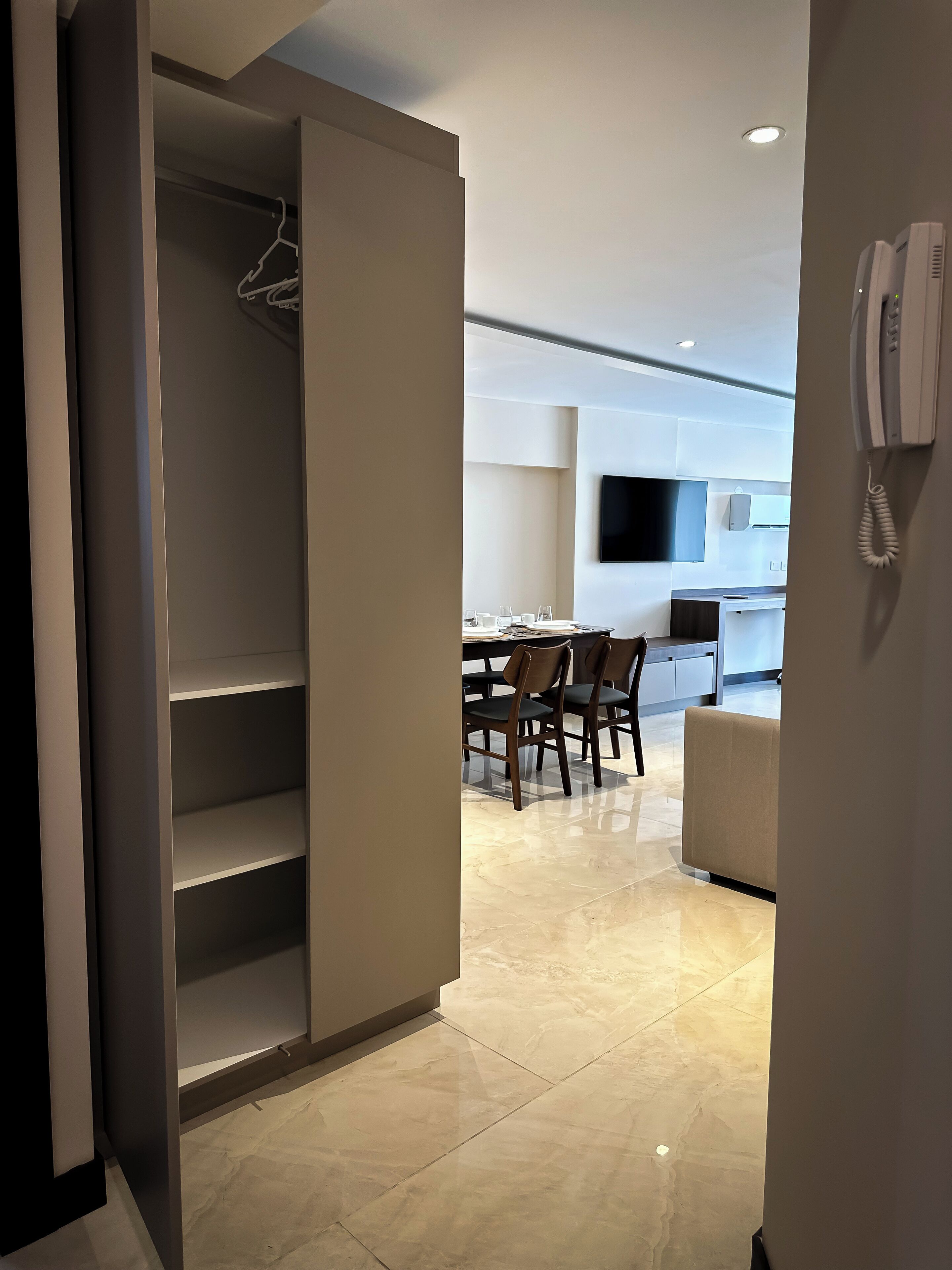 A modern kitchen with a flat-screen TV, a dining area with chairs, and a built-in oven.