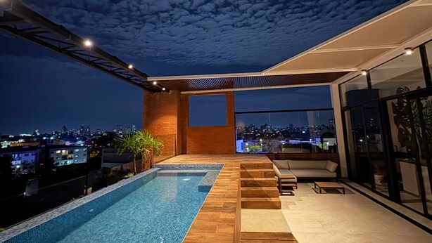 A modern rooftop pool with a city view, wooden flooring, and a seating area. - AMERICA APARTMENTS (Santa Cruz)