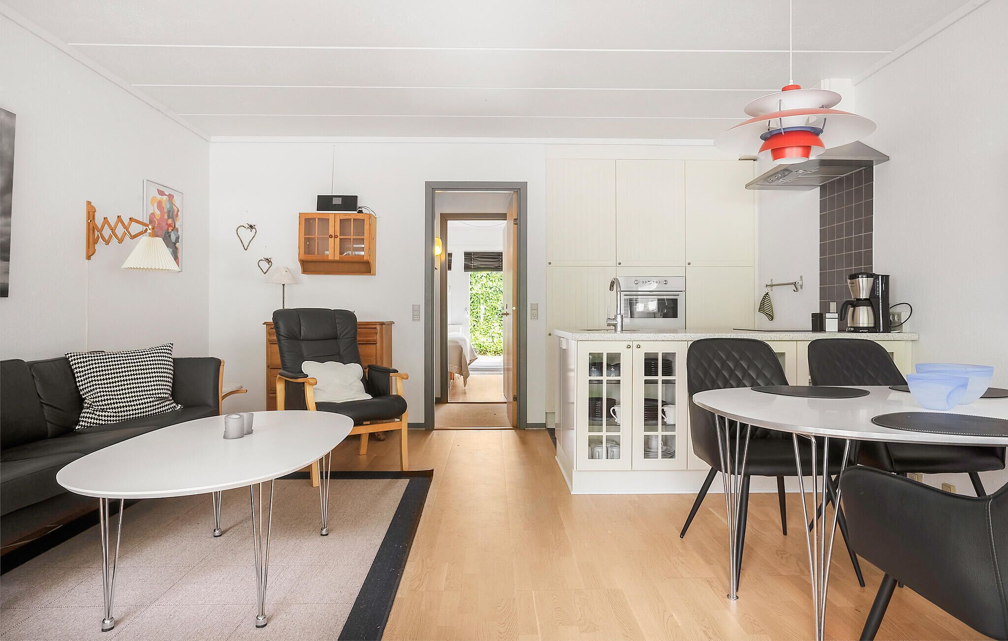 A modern living room with a sofa, a dining table, and a kitchen area with a stove and coffee maker.