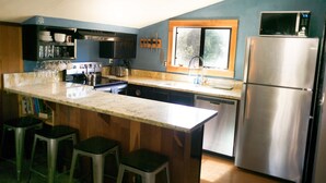 Una cocina con una isla grande, electrodomésticos de acero inoxidable y taburetes de bar.