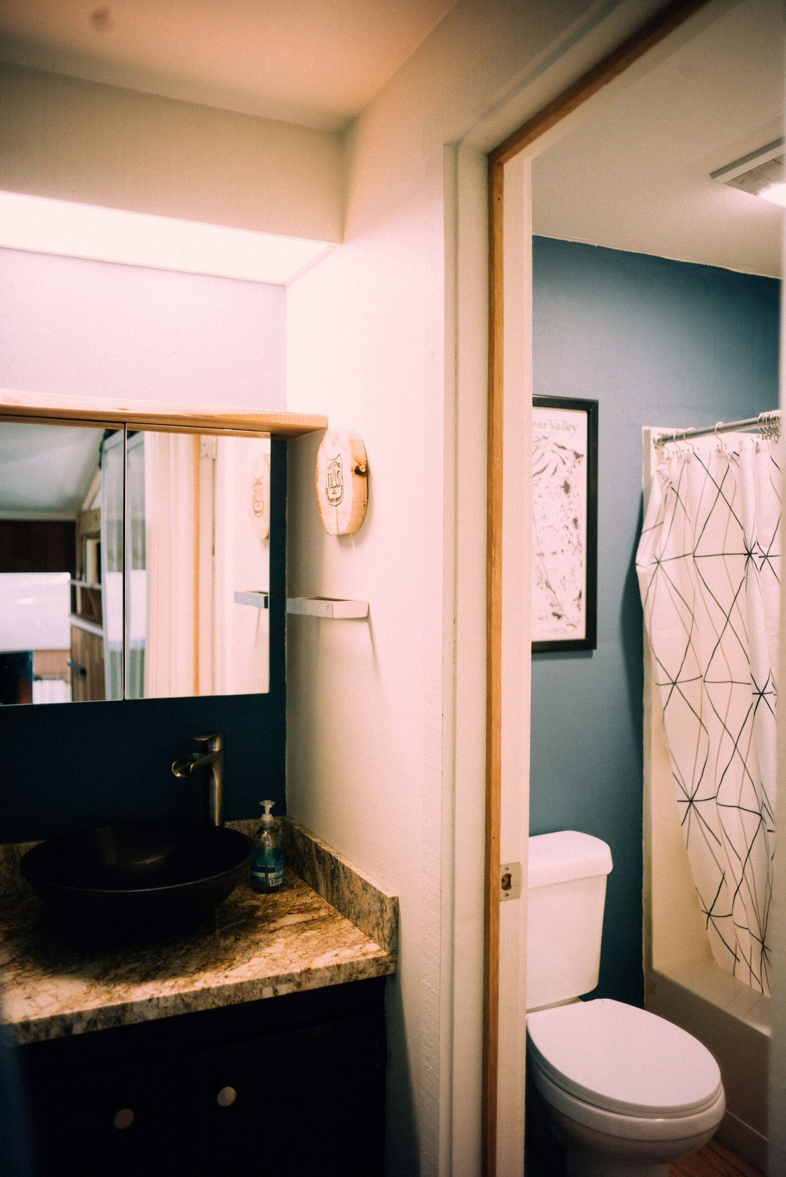 A bathroom with a sink, mirror, toilet, and shower curtain.