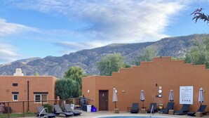 A pool area with a fenced pool, lounge chairs, and a view of mountains. - Luxury top-floor Penthouse with private dock, pool and stunning lake views. (Osoyoos)