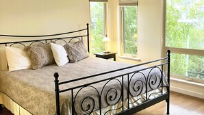 A bedroom with a bed, a ceiling fan, and large windows. - Luxury top-floor Penthouse with private dock, pool and stunning lake views. (Osoyoos)
