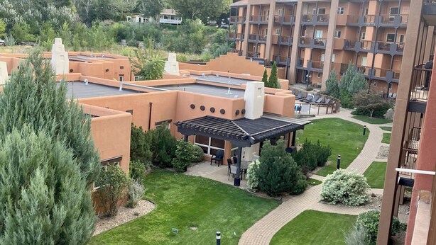 A residential area with a building featuring a rooftop terrace, a covered outdoor seating area, and a well-maintained lawn. - Luxury top-floor Penthouse with private dock, pool and stunning lake views. (Osoyoos)