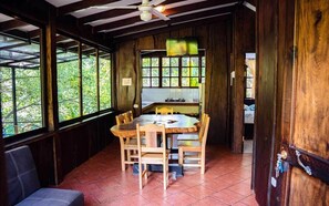 Ein Essbereich mit Holzboden, einem runden Tisch, Stühlen, einem Deckenventilator und großen Fenstern.