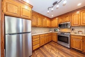A kitchen with wooden cabinets, stainless steel appliances, a microwave, and a gas stove. - Yosemite+Bass Lake -Hot tub,Game room,BBQ (Oakhurst)