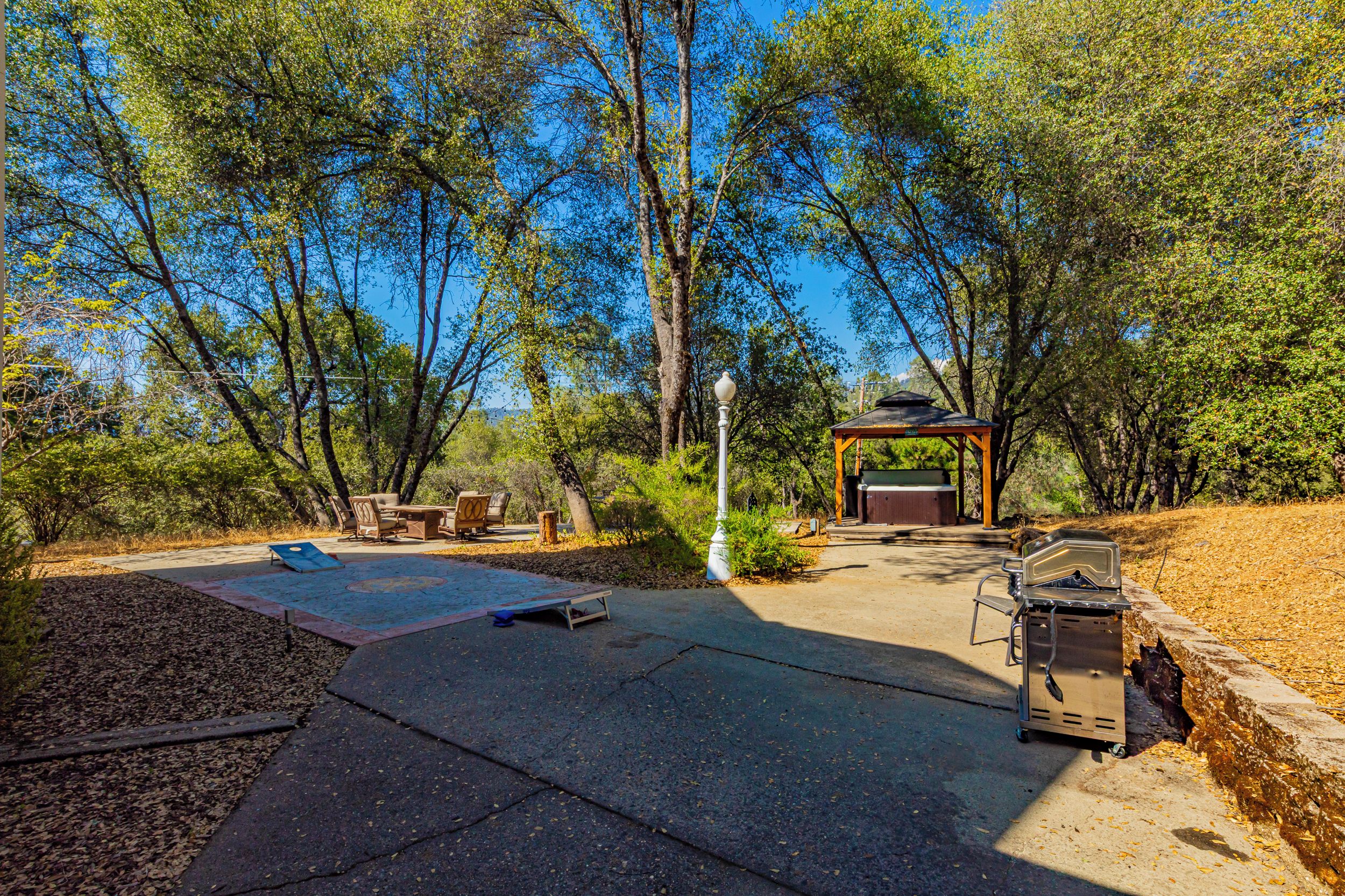 An outdoor patio area with a barbecue grill, seating, and a gazebo.