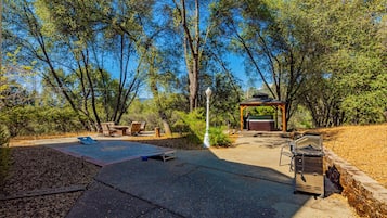 An outdoor patio area with a barbecue grill, seating, and a gazebo.