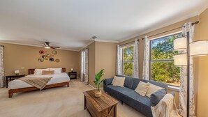 A bedroom with a bed, a sofa, a coffee table, and a window with curtains.