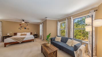 Une chambre à coucher avec un lit, un canapé, une table basse et une fenêtre avec des rideaux.