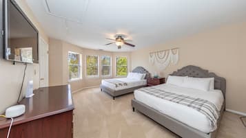 A bedroom with two beds, a ceiling fan, a desk with a computer, and a large window.