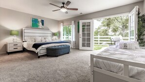 A bedroom with a large bed, a nightstand, a ceiling fan, and a view of the outdoors through a sliding glass door. - Yosemite+Bass Lake -Hot tub,Game room,BBQ (Oakhurst)