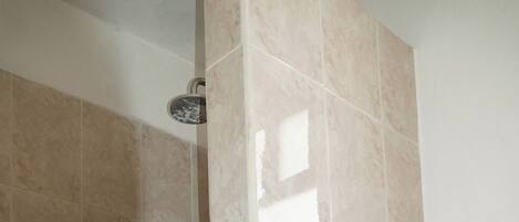 Un baño con paredes de azulejos color beige, ducha e inodoro.