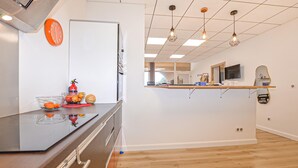 A modern kitchen with a black countertop, a white refrigerator, and a wooden floor. - Cozy apartment in Prunete with swimming pool (Prunete)