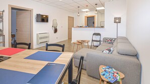 A modern living room with a wooden table, blue mats, a grey sofa, and a small wooden side table with magazines. - Cozy apartment in Prunete with swimming pool (Prunete)