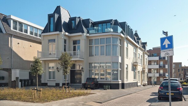 Un edificio moderno a più piani con un ingresso angolare, ampie finestre e un balcone.