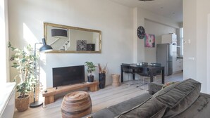Un soggiorno moderno con divano, televisione e zona pranzo con sedie e tavolo.